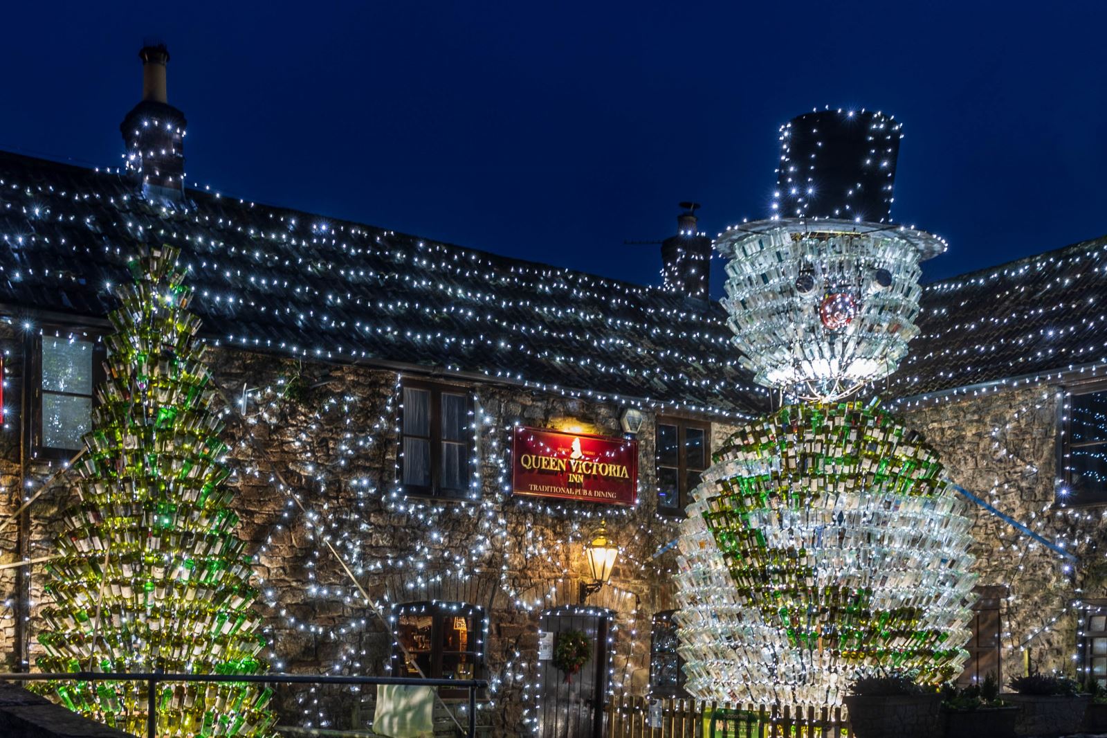 The Queen Victoria Pub in Priddy festooned in Christmas lights including a giant snowman and giant Christmas tree made out of empty wine bottles